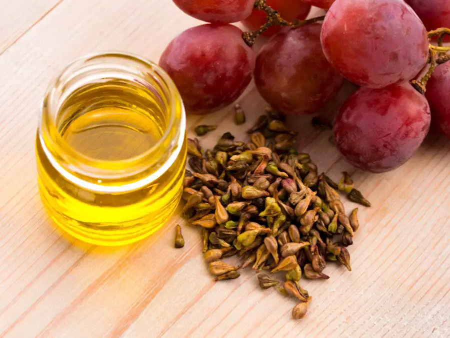 Photo of grapeseed oil, grapeseeds, and grapes