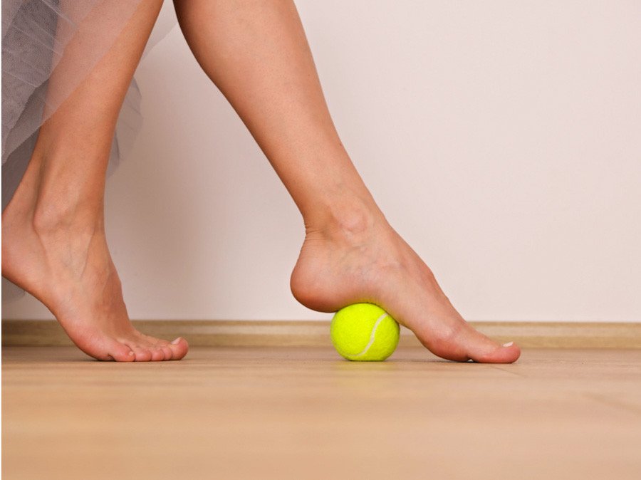 Picture of a woman massaging her feet with a tennis ball
